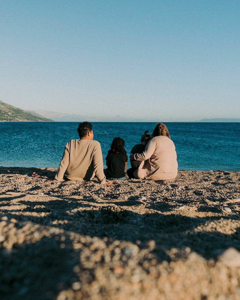 family sitting on beach